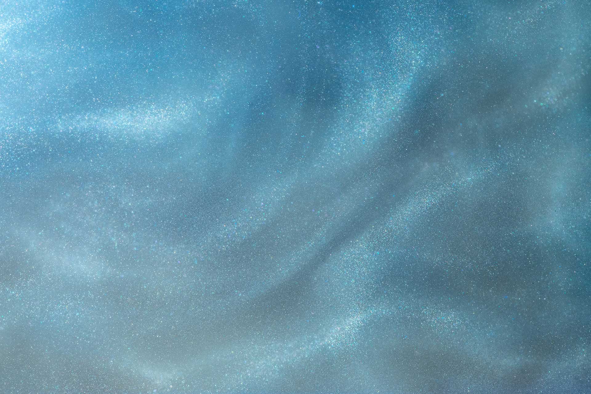 A shimmering blue and silver abstract background with wavy, textured patterns resembling clouds or ocean waves.